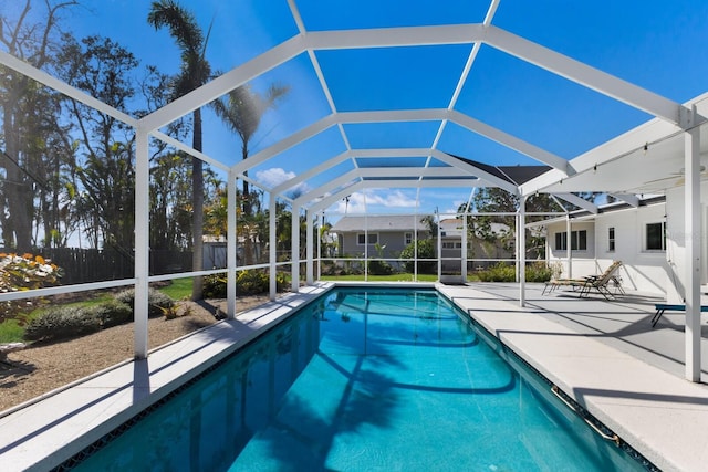 view of swimming pool with glass enclosure, fence, a fenced in pool, and a patio area