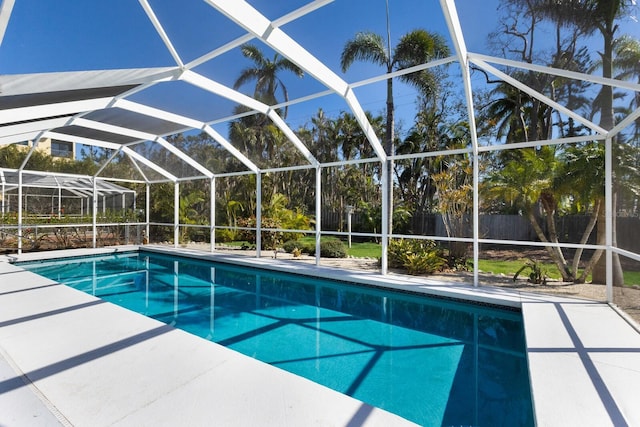 view of swimming pool featuring glass enclosure, a patio area, fence, and a fenced in pool