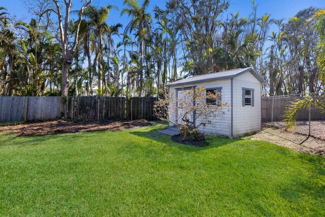 view of yard with a storage unit, an outdoor structure, and a fenced backyard