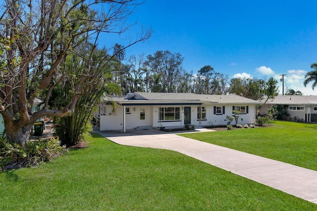 ranch-style home featuring concrete driveway and a front yard