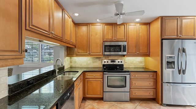 kitchen featuring a sink, dark stone counters, appliances with stainless steel finishes, light tile patterned floors, and decorative backsplash