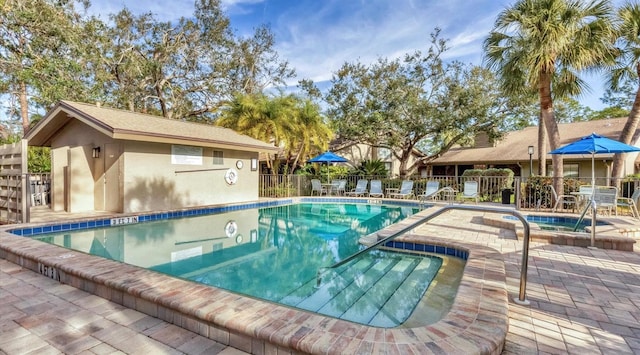 pool featuring a patio, fence, and a hot tub