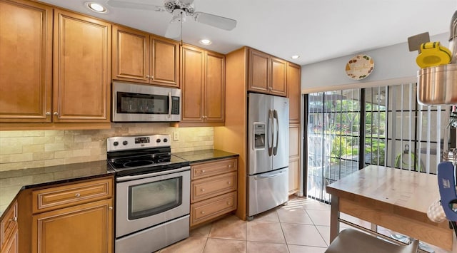 kitchen with brown cabinets, light tile patterned floors, tasteful backsplash, and stainless steel appliances