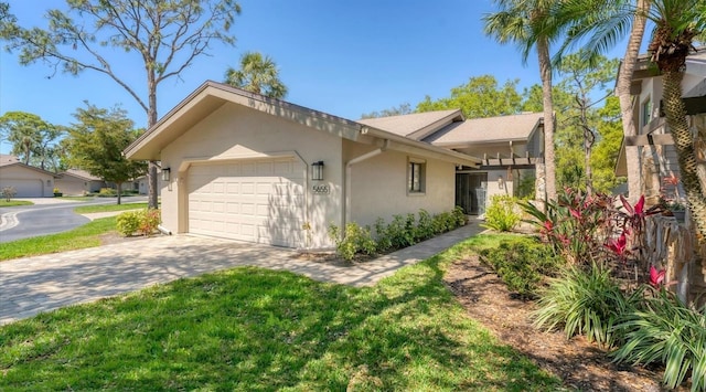 view of side of property featuring stucco siding, a garage, driveway, and a lawn