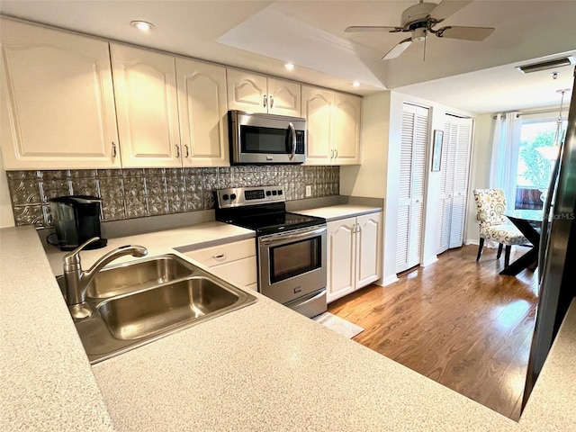 kitchen featuring visible vents, light wood-style flooring, a sink, stainless steel appliances, and white cabinetry