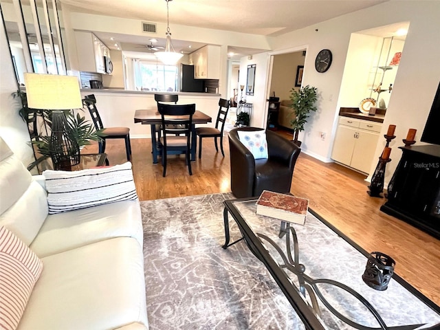 living room featuring visible vents, baseboards, and light wood-style flooring