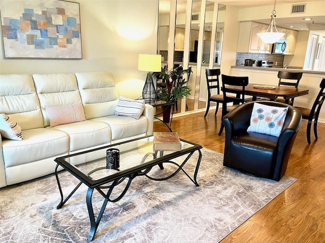 living room with visible vents, baseboards, and light wood-style floors