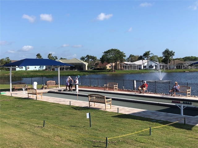 view of property's community with a lawn, fence, and a water view