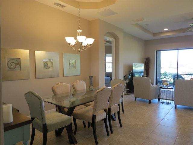 dining space with visible vents, a tray ceiling, light tile patterned flooring, arched walkways, and a chandelier