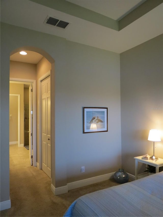 carpeted bedroom featuring arched walkways, visible vents, a closet, and baseboards