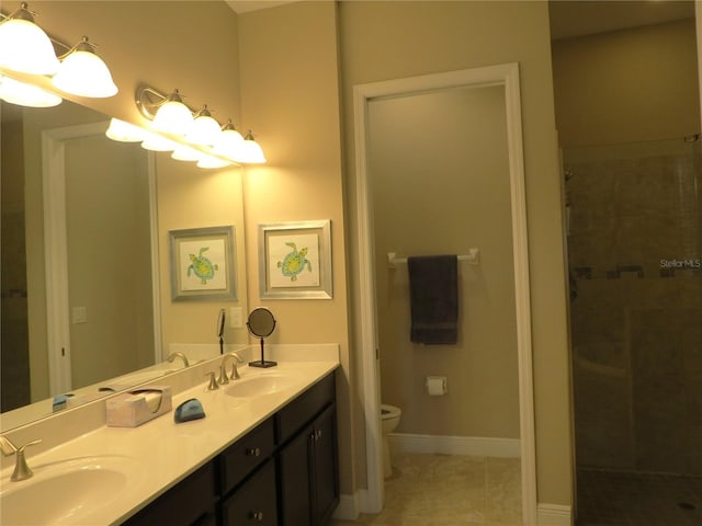 full bath with a sink, toilet, double vanity, and a tile shower