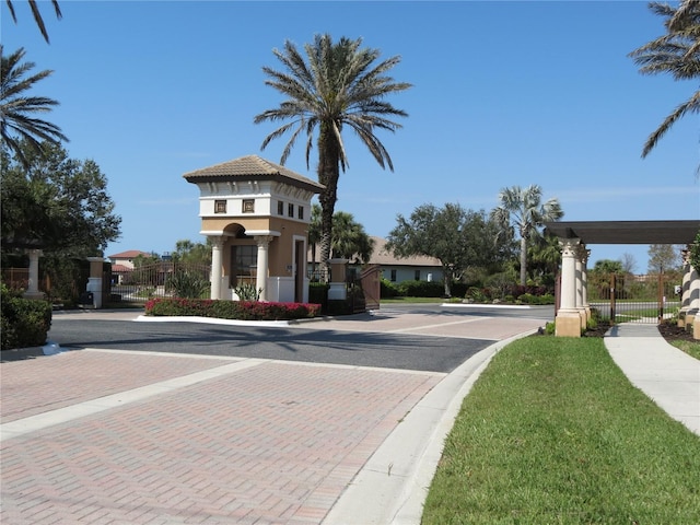 view of road featuring sidewalks, curbs, a gated entry, and a gate