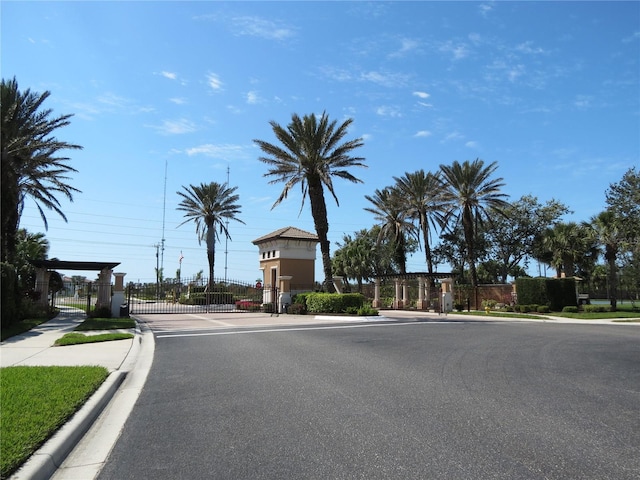 view of road featuring a gate, curbs, sidewalks, and a gated entry