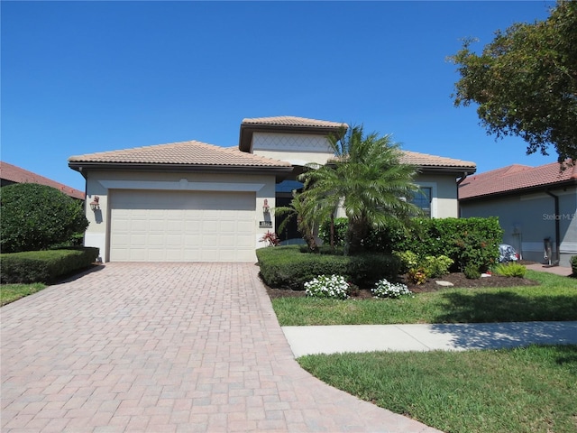 view of front facade featuring stucco siding, a tiled roof, an attached garage, and decorative driveway