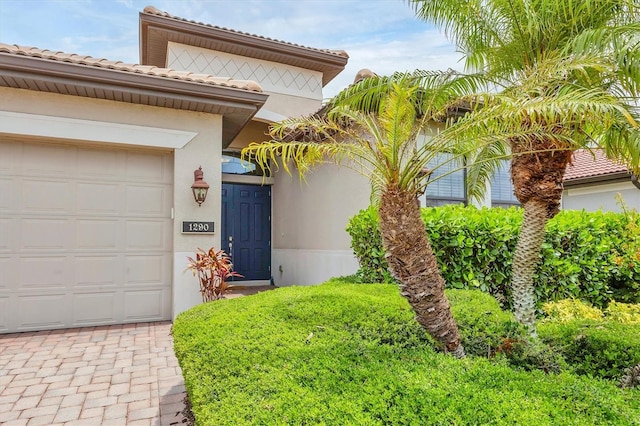 1290 Cielo Ct, North Venice, FL 34275 - doorway to property featuring an attached garage, stucco siding, a tile roof, and decorative driveway