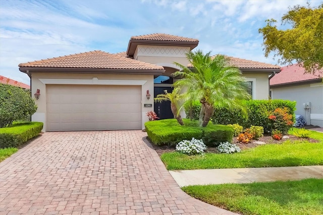 1290 Cielo Ct, North Venice, FL 34275 - mediterranean / spanish-style home featuring stucco siding, decorative driveway, a tiled roof, and a garage