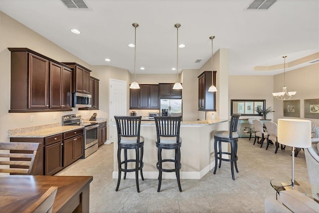 1290 Cielo Ct, North Venice, FL 34275 - kitchen with appliances with stainless steel finishes, dark brown cabinets, a breakfast bar area, hanging light fixtures, and a chandelier