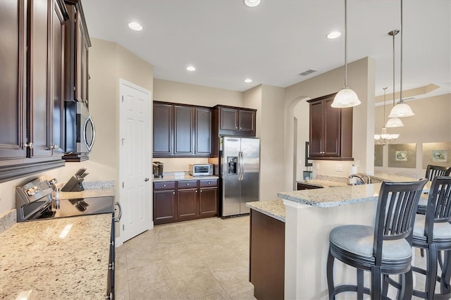 1290 Cielo Ct, North Venice, FL 34275 - kitchen featuring appliances with stainless steel finishes, dark brown cabinetry, arched walkways, a breakfast bar, and light stone counters