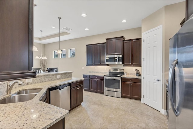 1290 Cielo Ct, North Venice, FL 34275 - kitchen featuring appliances with stainless steel finishes, a sink, pendant lighting, dark brown cabinetry, and light stone countertops