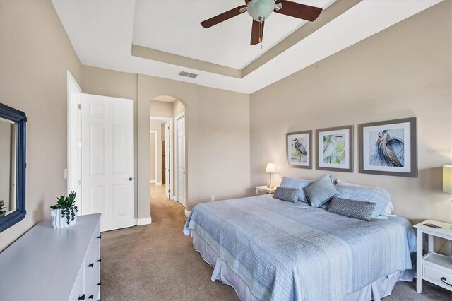 1290 Cielo Ct, North Venice, FL 34275 - bedroom with carpet floors, arched walkways, baseboards, a raised ceiling, and ceiling fan