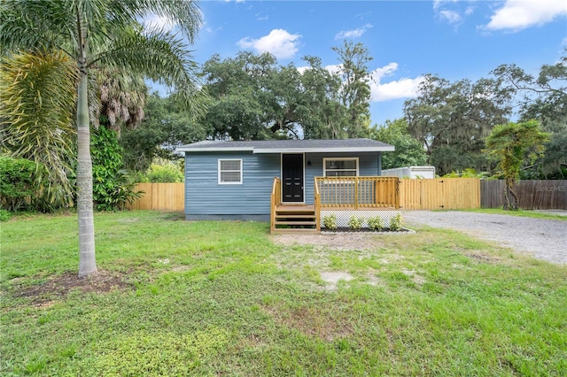 view of front of house featuring a deck, driveway, a front lawn, and fence