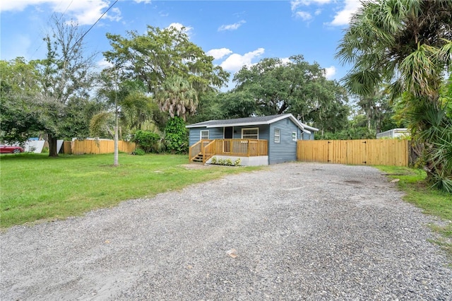 view of front of house with driveway, a front lawn, and fence