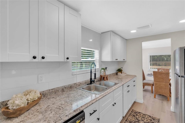 kitchen featuring a sink, visible vents, white cabinets, and freestanding refrigerator