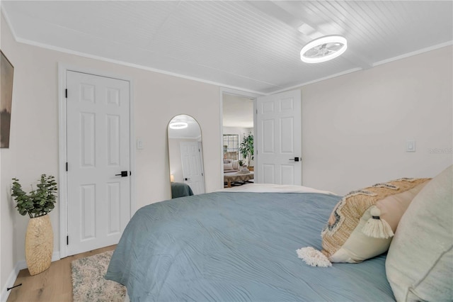 bedroom featuring baseboards, wood finished floors, and crown molding