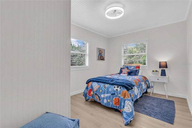 bedroom featuring multiple windows, wood finished floors, baseboards, and ornamental molding