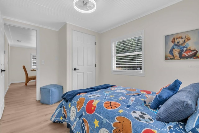 bedroom with wood finished floors, visible vents, and ornamental molding