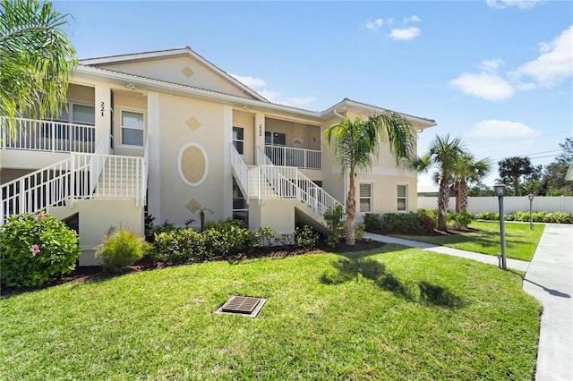 view of front of home featuring stairway, a front yard, and stucco siding