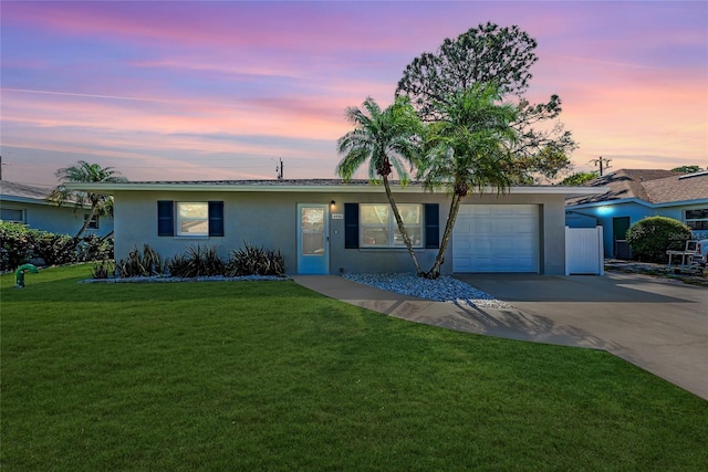 ranch-style house with stucco siding, a garage, concrete driveway, and a front lawn