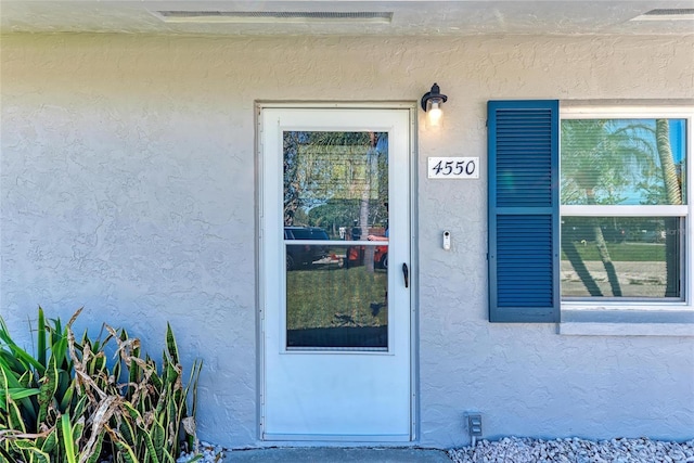 doorway to property featuring stucco siding