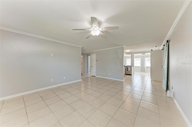 empty room featuring ceiling fan, baseboards, a barn door, and ornamental molding