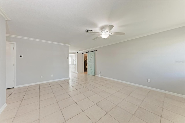 spare room with visible vents, a ceiling fan, a barn door, crown molding, and baseboards