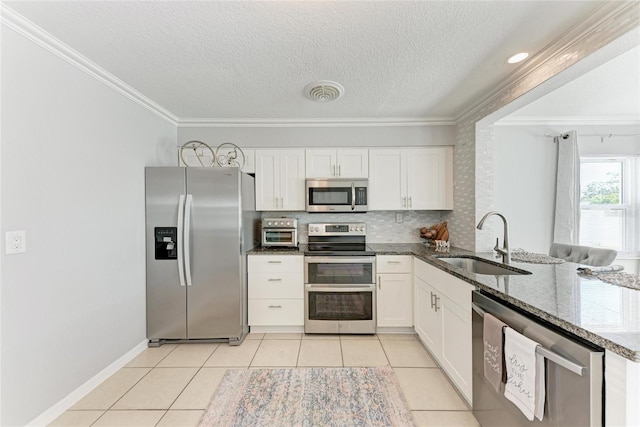 kitchen featuring visible vents, light tile patterned floors, white cabinets, stainless steel appliances, and a sink