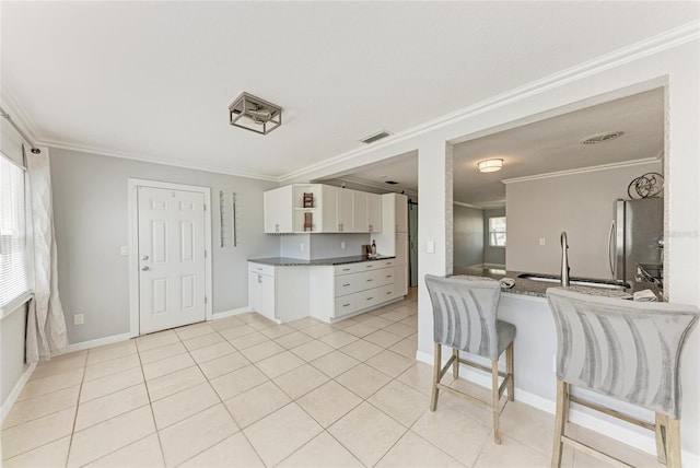 kitchen with ornamental molding, open shelves, white cabinetry, freestanding refrigerator, and light tile patterned floors