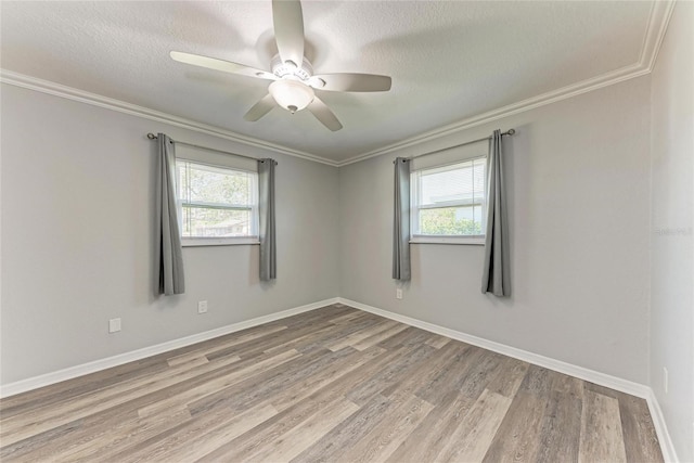 empty room featuring crown molding, wood finished floors, and a healthy amount of sunlight