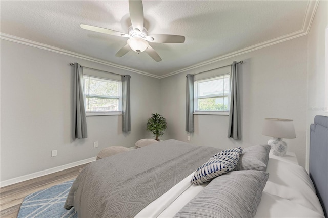 bedroom with multiple windows, crown molding, baseboards, and wood finished floors