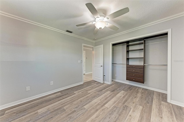 unfurnished bedroom featuring visible vents, a textured ceiling, a closet, light wood-style floors, and crown molding