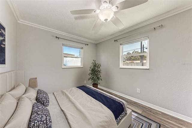 bedroom with wood finished floors, baseboards, ceiling fan, a textured ceiling, and crown molding