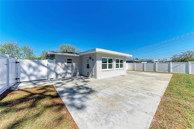 view of front of house featuring stucco siding, fence, a patio area, and a gate