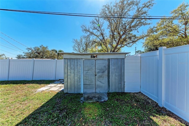 view of yard featuring an outbuilding, a fenced backyard, and a shed