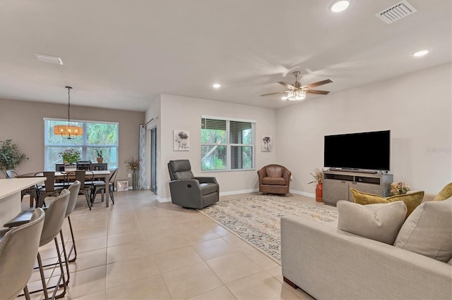 living room featuring light tile patterned floors, recessed lighting, visible vents, baseboards, and ceiling fan with notable chandelier