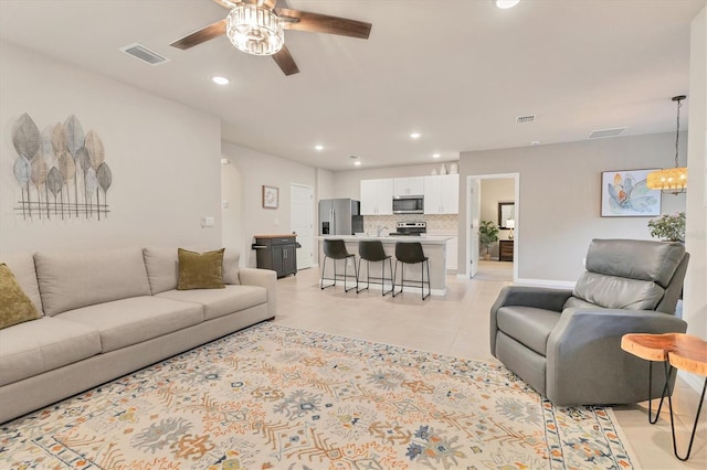 living area featuring ceiling fan with notable chandelier, visible vents, and recessed lighting