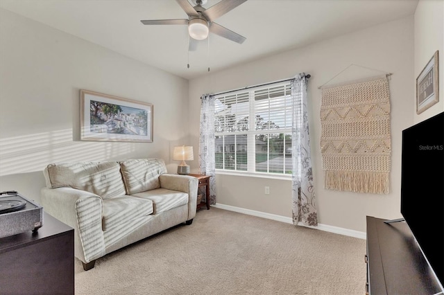 living area with light carpet, baseboards, and a ceiling fan