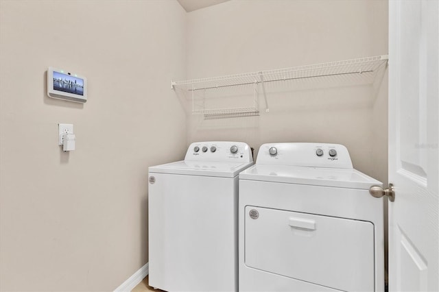 clothes washing area with laundry area, baseboards, and washing machine and clothes dryer