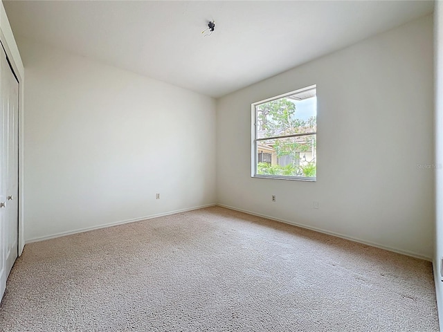 interior space featuring a closet, light carpet, and baseboards