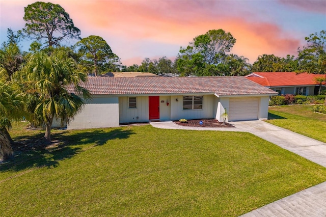 ranch-style home featuring a tile roof, concrete driveway, a garage, and a front yard