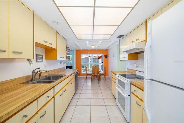 kitchen featuring under cabinet range hood, white appliances, cream cabinetry, and a sink